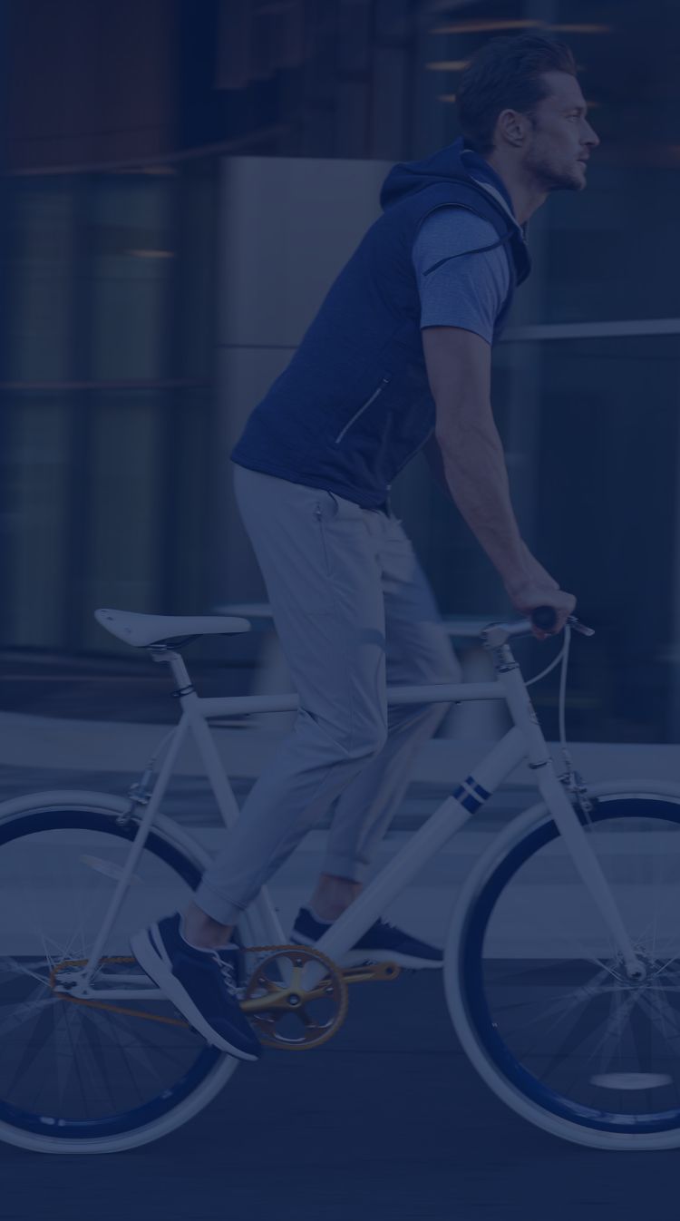 Man riding a bicycle wearing stylish performance-material clothing.